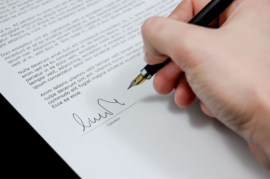 person holding fountain pen with white printing paper, document