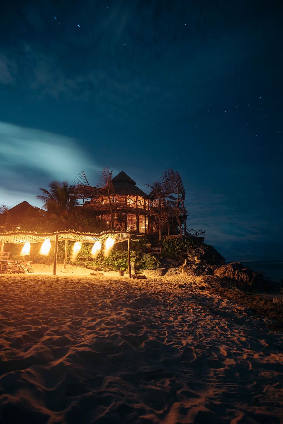 brown tent on brown sand under blue sky during nightime, brown wooden canopy tent with lights on beach HD wallpaper