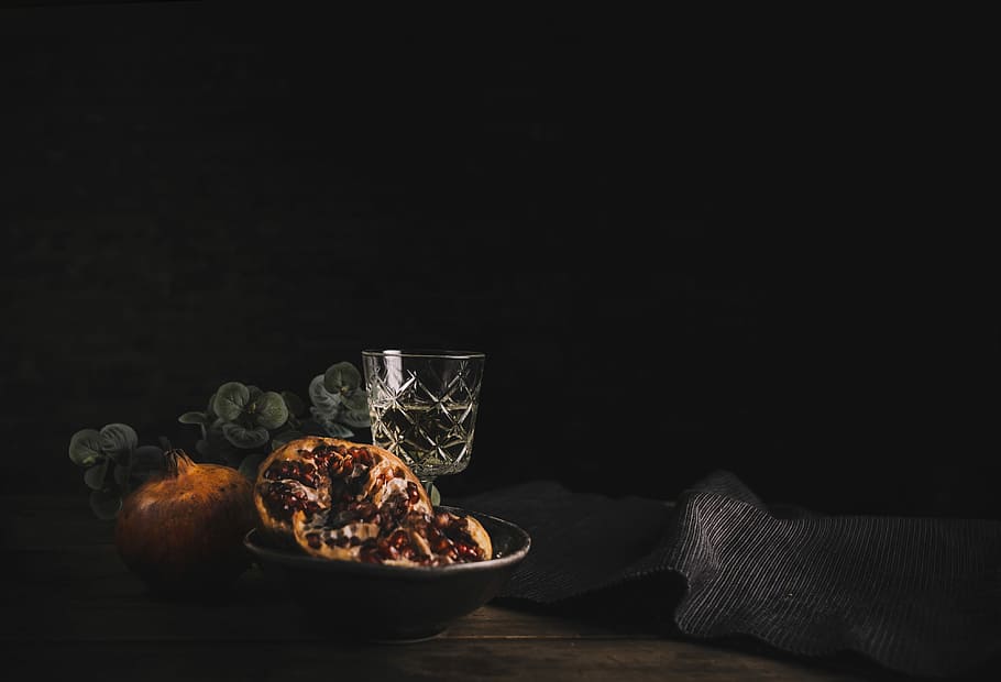 pretzels on black ceramic bowl, glass goblet on brown wooden table
