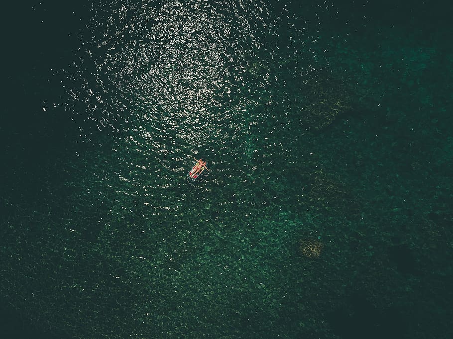 person riding on boat in aerial photogrphy, top view photography of person lying on waterbed