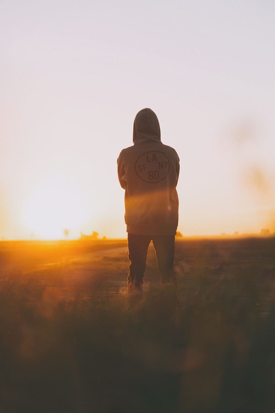 person in hoodie standing on field, focus photography of person standing facing sun ligh t HD wallpaper