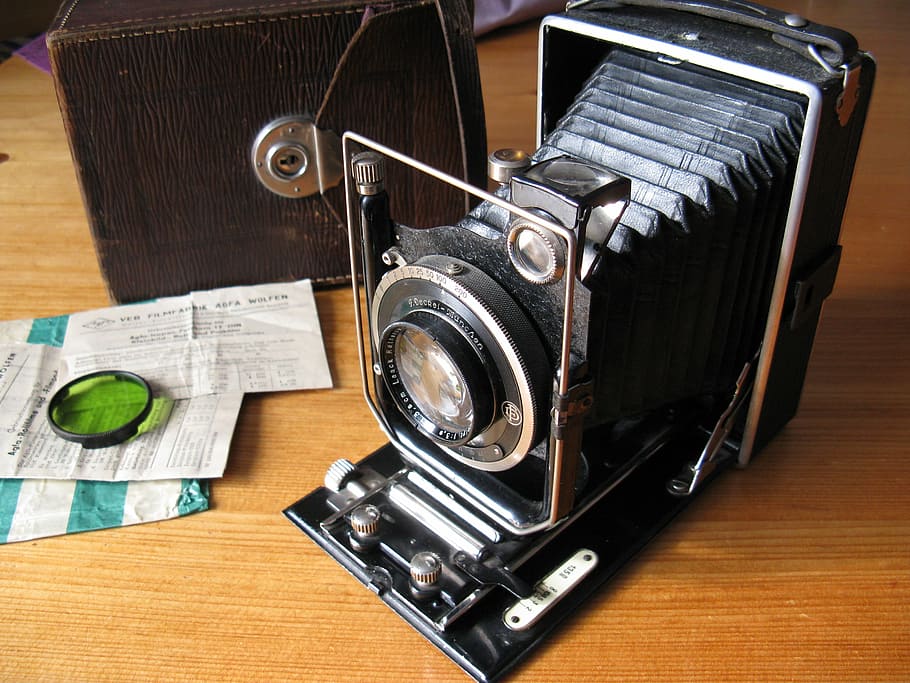 black land camera with green lens cover on brown wooden board