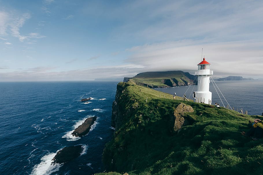 lighthouse near body of water, white lighthouse over green mountain HD wallpaper
