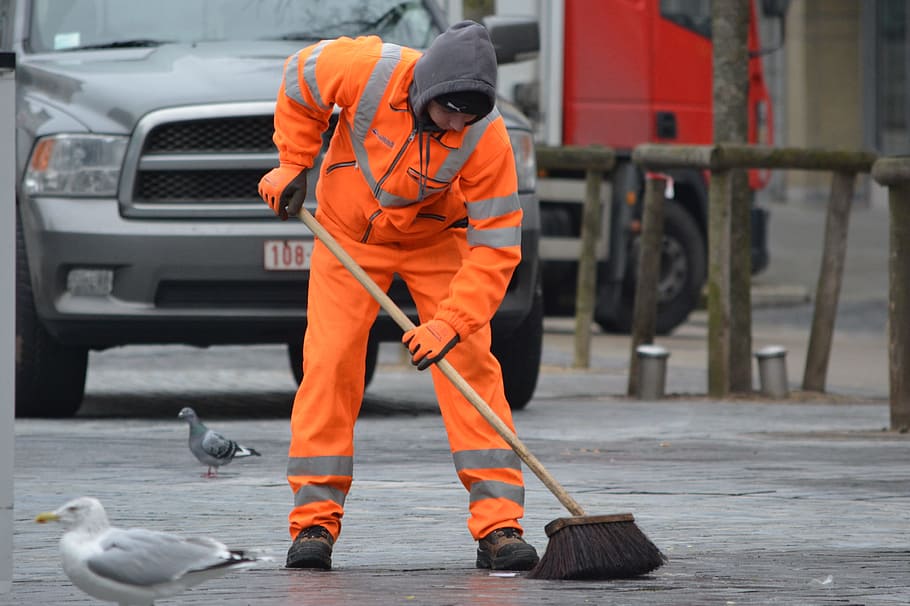 man sweeping the road near pigeons and vehicle, orange, brush
