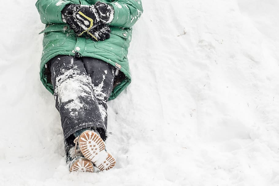 person wearing green windbreaker bubble jacket and black jeans sitting on snow at daytime HD wallpaper