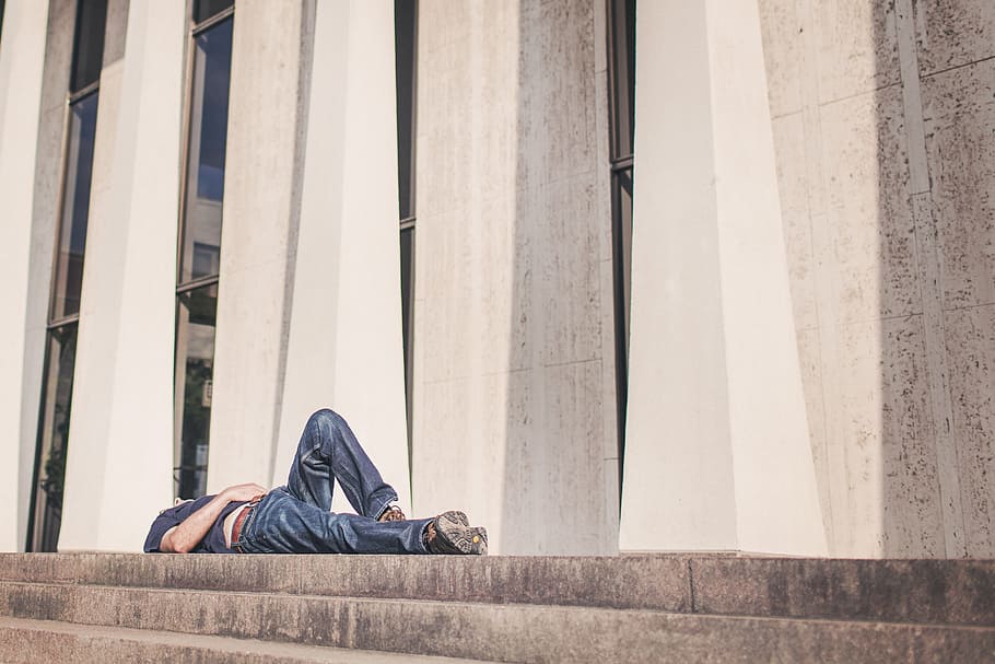 man laying on concrete pavement with stairs near building, resting HD wallpaper