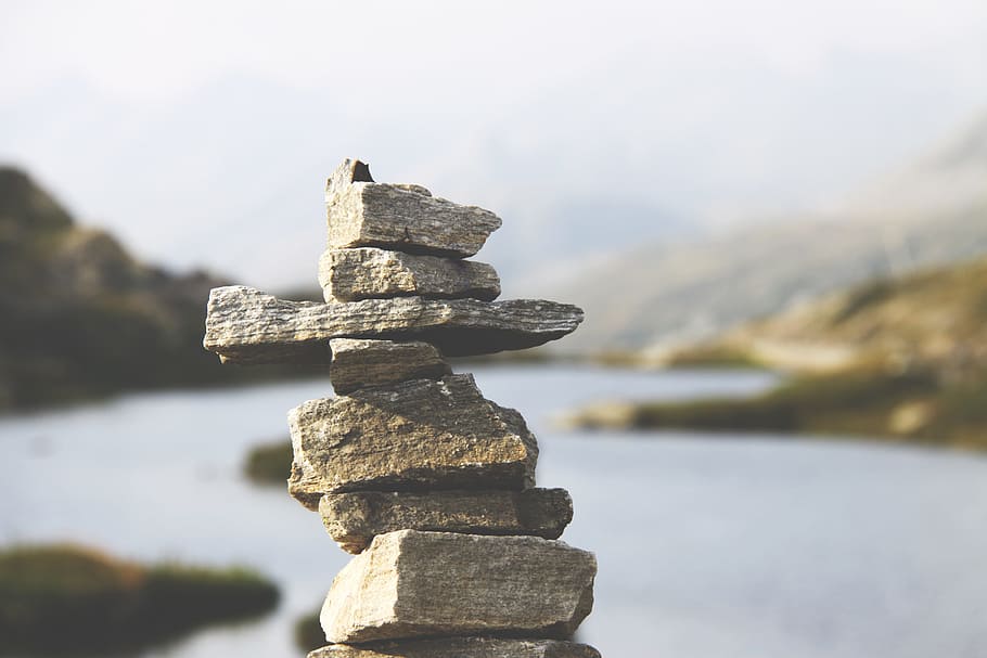 gray file stone during daytime, shallow photography of cairn with background of mountain and large body of water during daytime HD wallpaper
