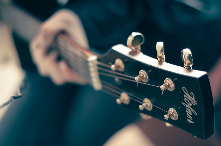 selective focus photography of person playing guitar, classical guitar