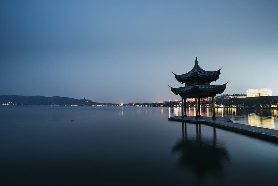 gray pier on body of water, photo of brown wooden dock with shed near calm body of water during nighttime HD wallpaper