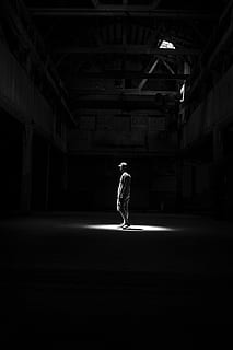 grayscale photography of man standing in room with dim light HD wallpaper