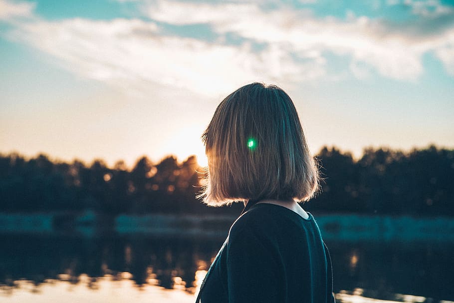 woman standing near lake during daytime, woman looking at distance of trees and body of water under blue and white sky HD wallpaper