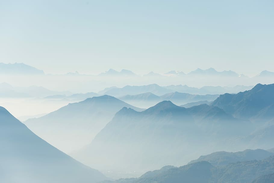 mountains covered with fogs, photo of mountain surrounded by fog during daytime