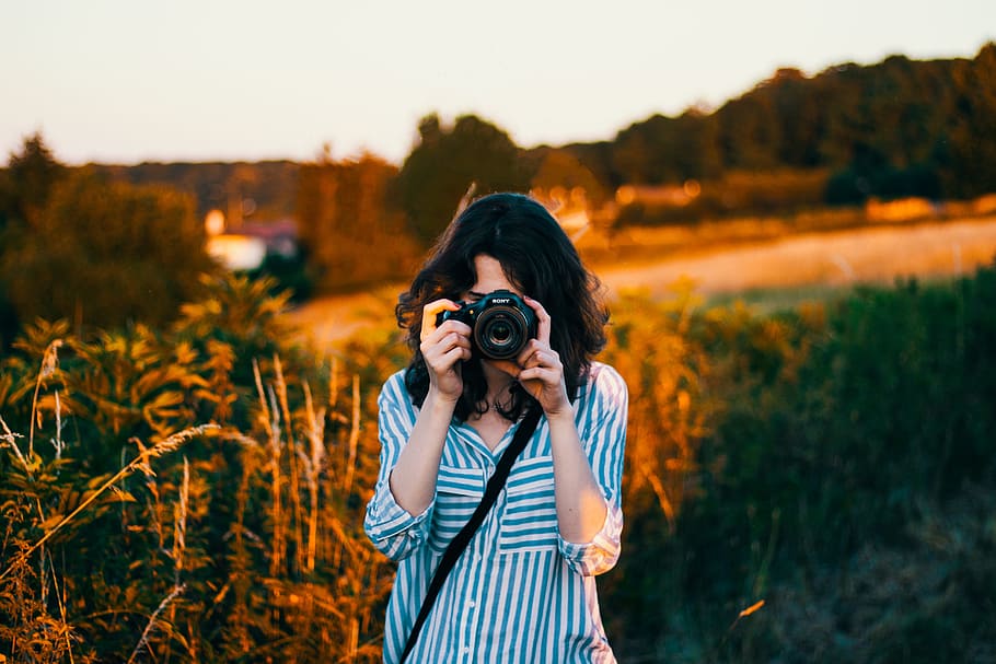 selective focus photography of woman wearing teal and white striped elbow-sleeved blouse, woman's taking pictures HD wallpaper