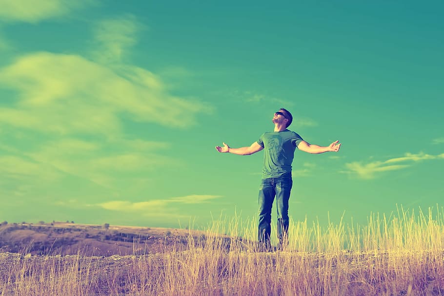 man in green crew-neck t-shirt ;blue denim jeans standing on brown grass field under blue sky photo, HD wallpaper