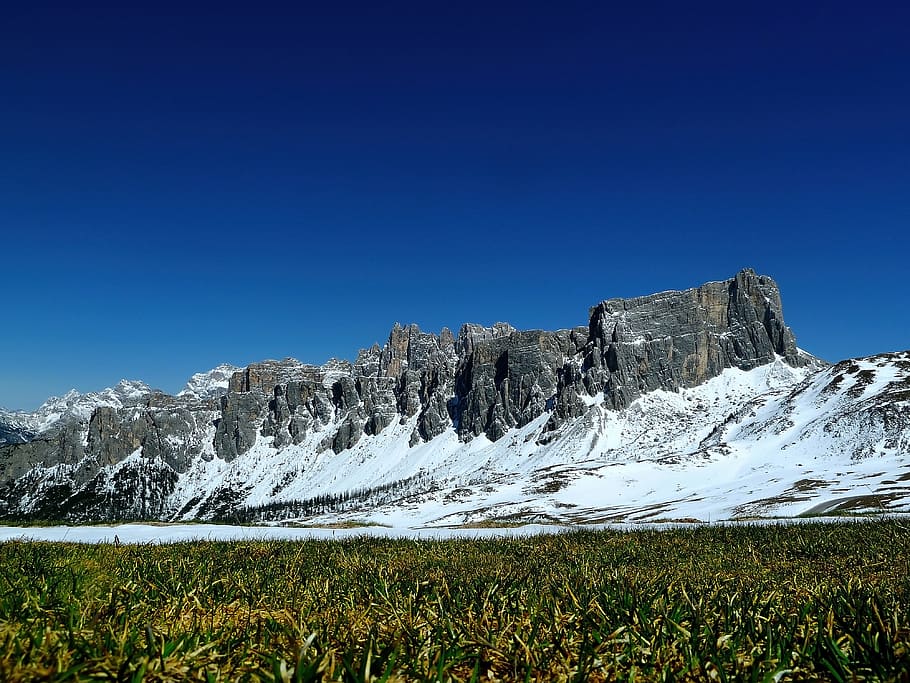 Green Fields Under Grey Rock Formations Covered With Snow, blue HD wallpaper