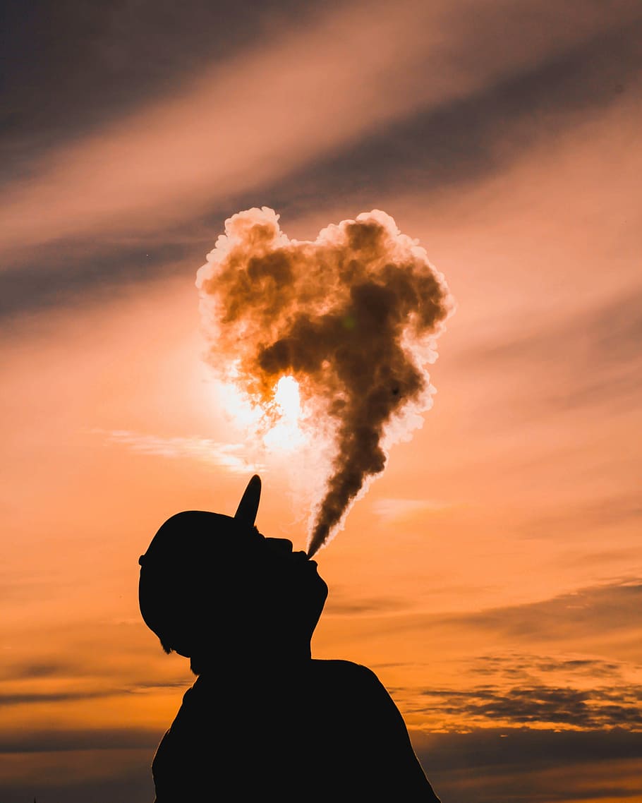 silhouette of man vaping during sunset, silhouette of man blowing smoke