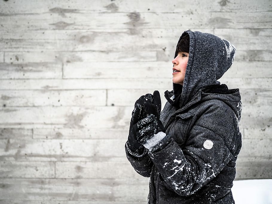 person wearing black hooded jacket standing beside grey wall, woman taking selfie HD wallpaper
