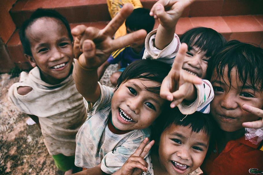 five children smiling while doing peace hand sign, tilt shift lens photography of children's showing their hands