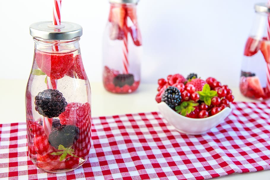 clear glass mason jar beside white ceramic bowl, berries, erfrischungsgetränk
