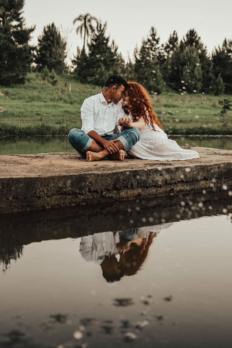 man and woman sitting while holding hands, couple sitting near body of water HD wallpaper