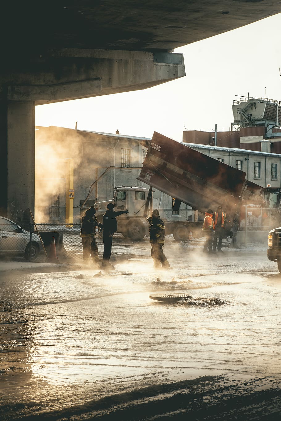 firemen walking on flooded road with cars and trucks, gray truck near gray concrete building HD wallpaper