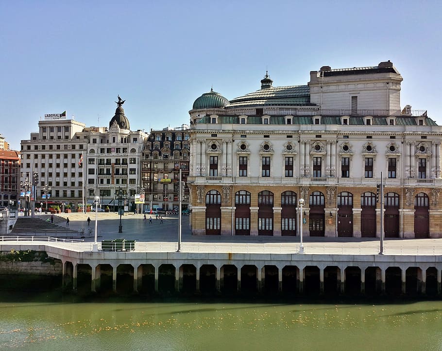 white and brown concrete buildings near calm body of water HD wallpaper