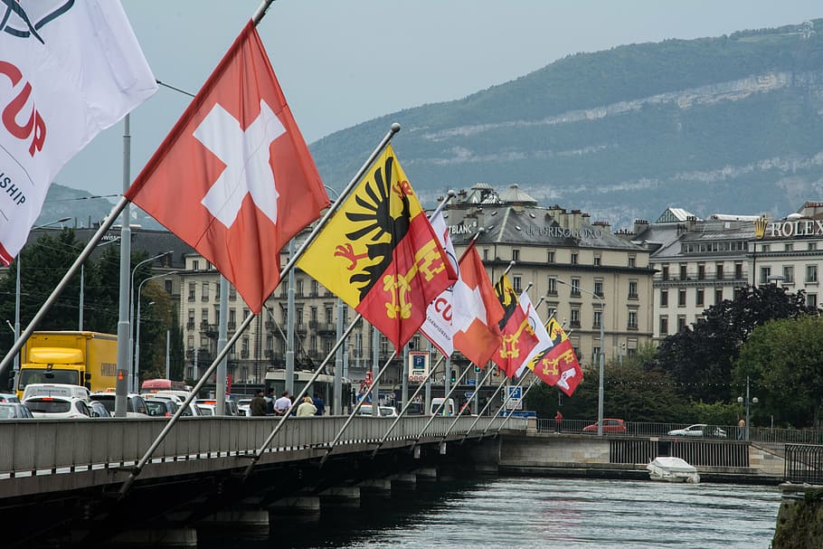 assorted-color flag post on gray bridge near water during daytime HD wallpaper