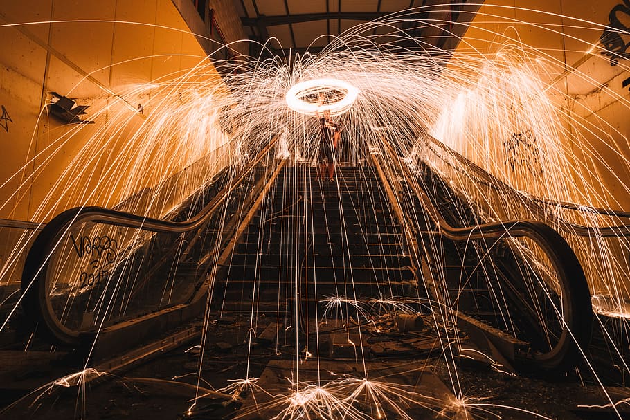 steel wool photography of man standing on stairs, man doing fire poi dance on escalator HD wallpaper