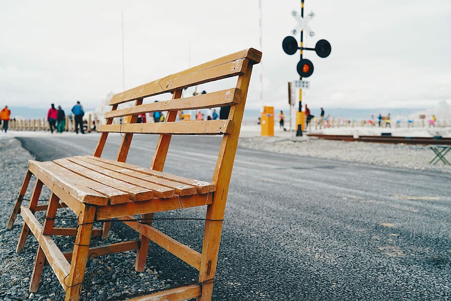 selective focus photography of brown wooden bench beside asphalt road during daytime, brown wooden bench placed on sidewalk HD wallpaper