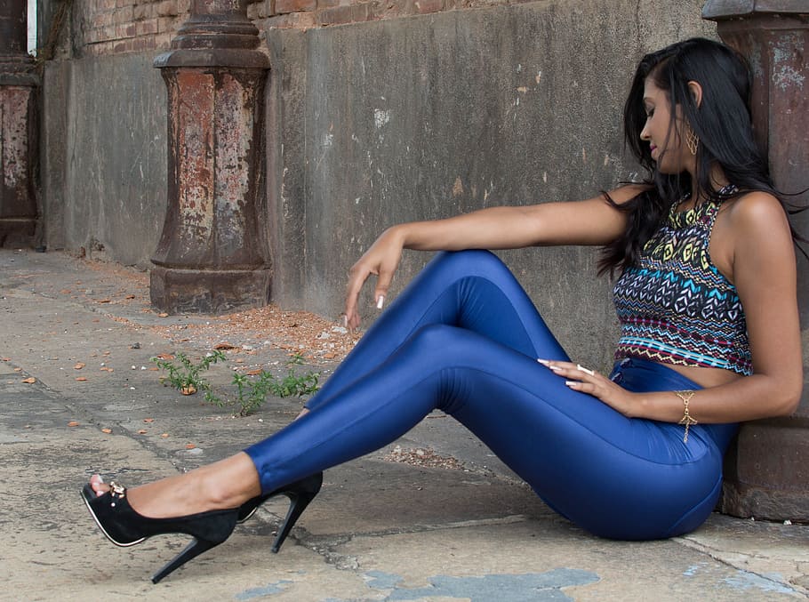 woman wearing blue leggings sitting on concrete pavement leaning on brown wall, HD wallpaper