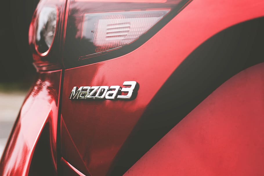 closeup photography of red Mazda 3 vehicle, close-up photo of Mazda 3 emblem