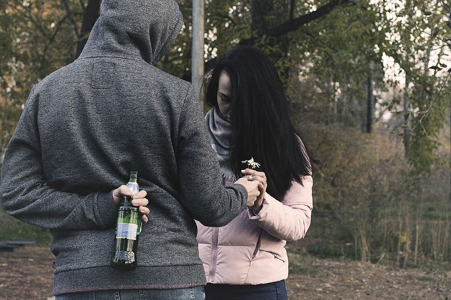 woman holding bottle on his back while giving flower to woman, HD wallpaper