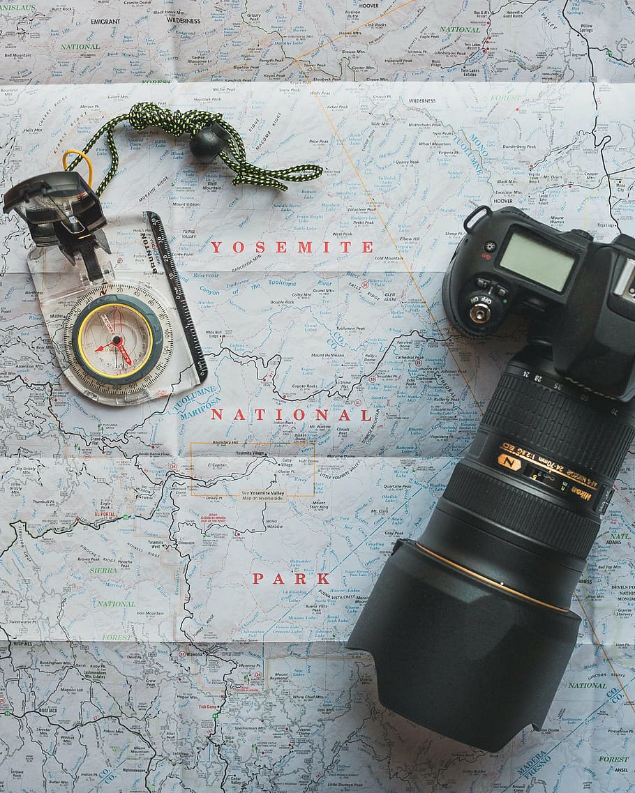 black Nikon DSLR camera on map, compass, exploration, guidance
