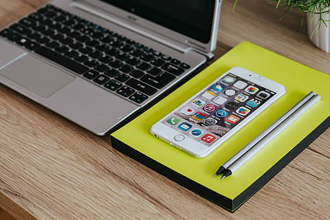 Silver Acer laptop, a white Apple iPhone and a notepad on a wooden desk HD wallpaper