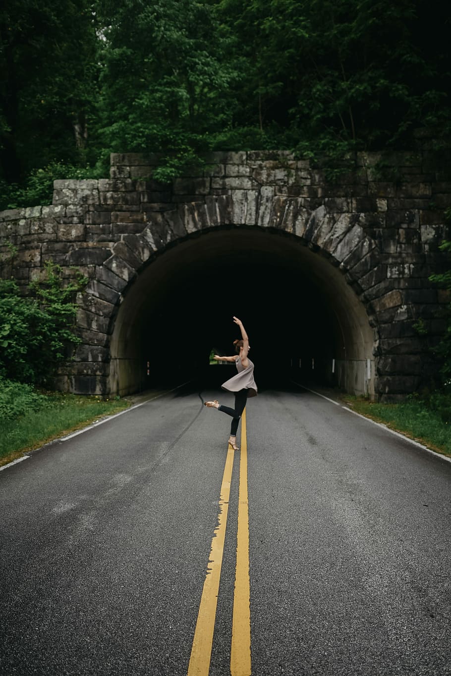 woman in ballet position nearby tunnel, woman posing on road