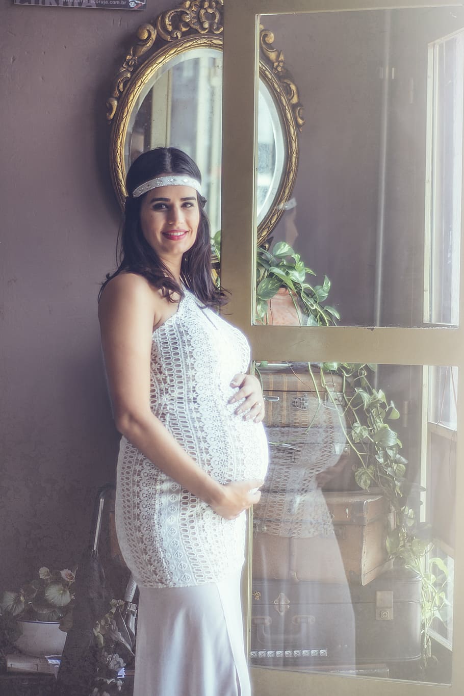woman in white halter top standing near the mirror, pregnant woman
