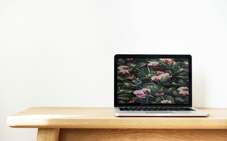 turned on black and gray laptop computer displaying flowers on brown wooden table HD wallpaper