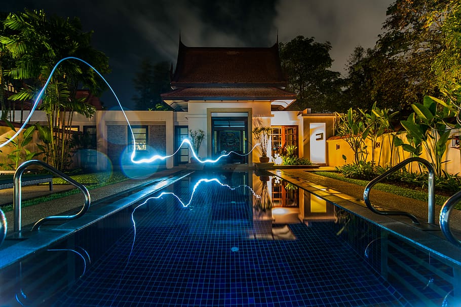 reflection of blue light crossing above pool near house during nighttime, time laps photography of light crossing outdoor pool HD wallpaper