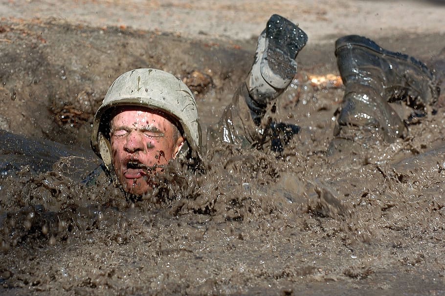 soldier lying prone in mud during daytime, crawl, obstacle, military