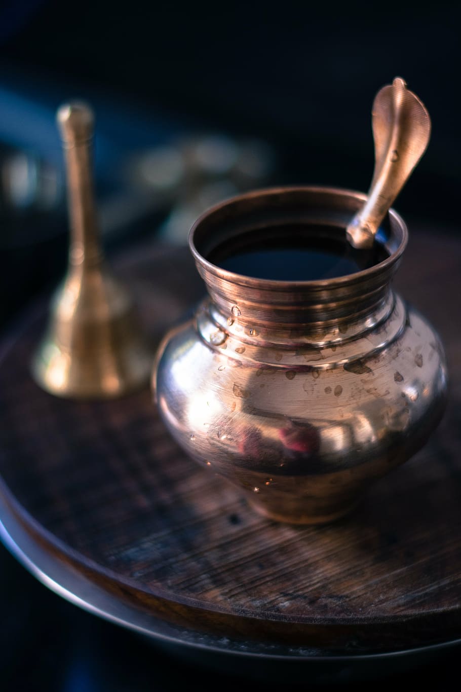 selective focus photography of small jar on brown table beside hand bell