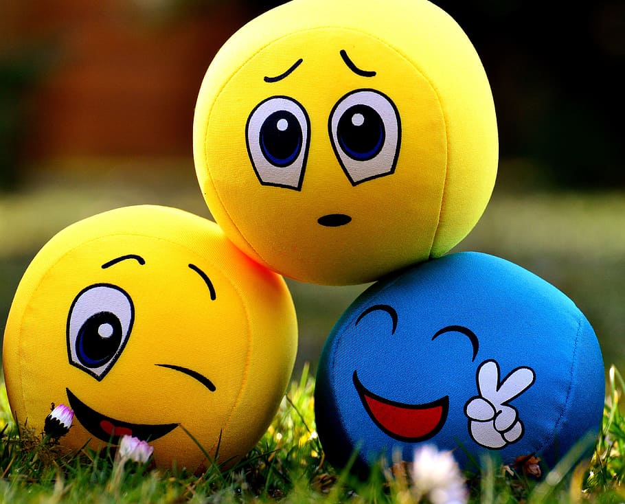 three assorted-color ball plush toy on grass, smilies, emotions