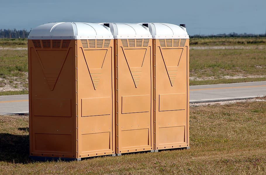 three brown containers, portable toilets, outdoors, events, public
