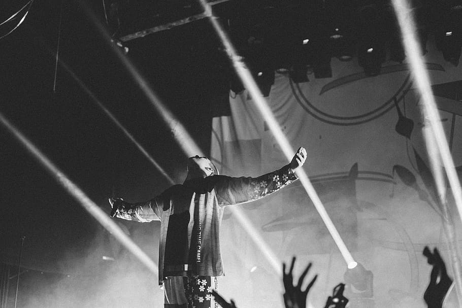 grayscale photo of man extended his arms surrounded by people, man lifting his arms on the stage HD wallpaper