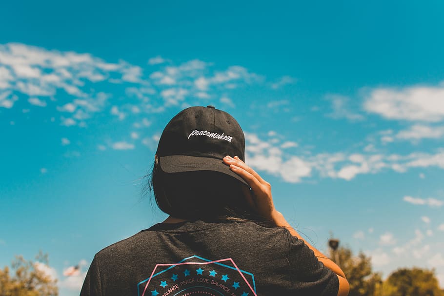 woman wearing black cap during daytime, close-up photo of woman wearing black fitted cap under blue sky during daytime HD wallpaper