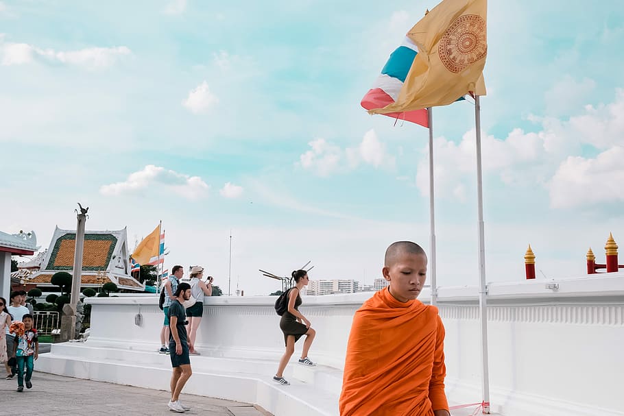 monk standing near white wall, boy walking near flag post, child HD wallpaper