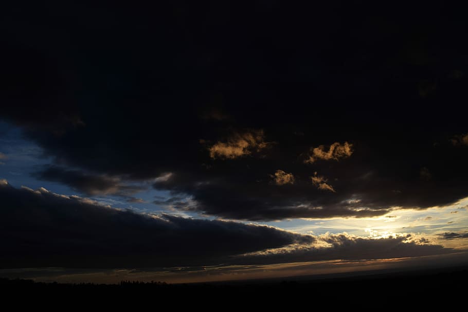 sunset covered with dark clouds, open field under blue, black, and yellow cloudy skies HD wallpaper