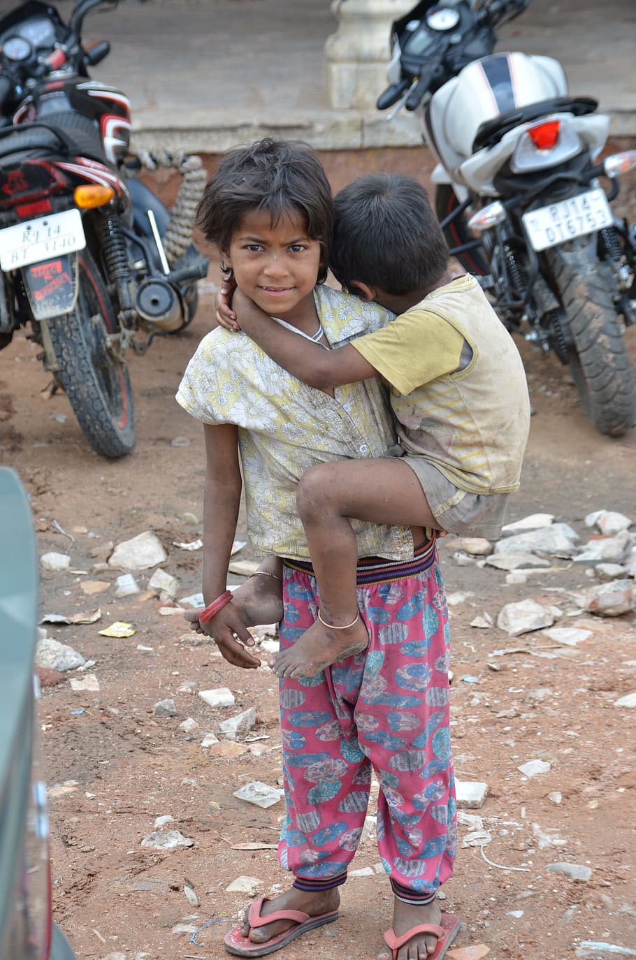 child carrying toddler while standing near parked motorcycles during daytime HD wallpaper