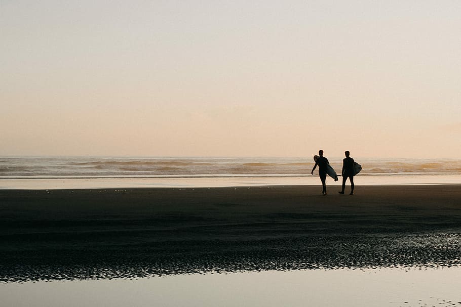 two persons holding surfboards on shoreline, two person walking on beach with surfboard HD wallpaper