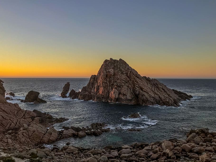 rock formation on sea during sunset, body of water hitting brown rock formation HD wallpaper
