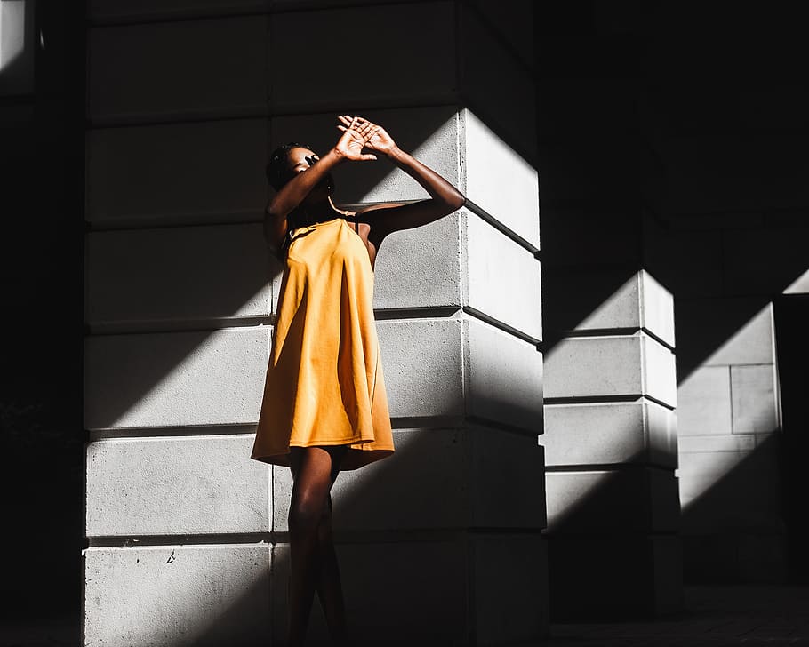 woman in orange dress and standing near white post, woman wearing yellow mini dress on grey concrete post HD wallpaper